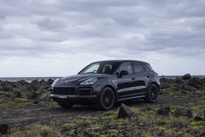 Black Porsche Cayenne GTS SUV on a rocky coast