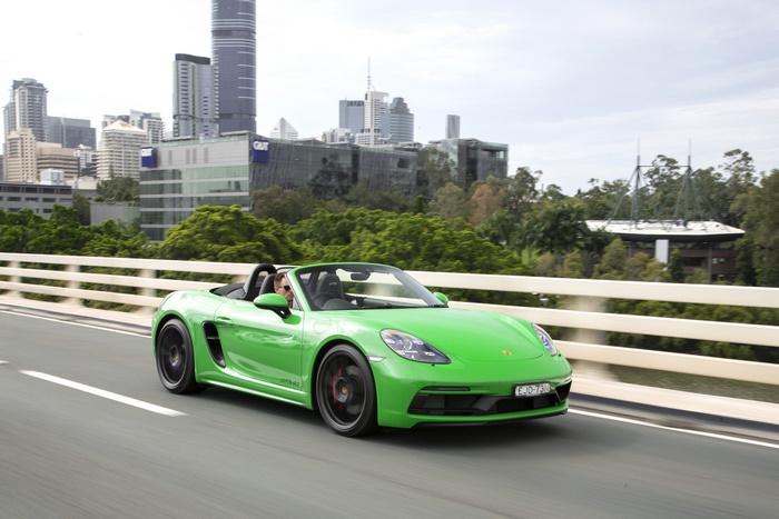 Green Porsche 718 Boxster GTS 4.0 driving on a bridge
