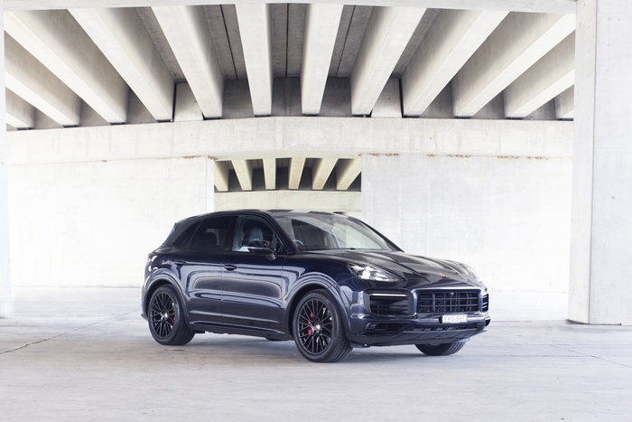 Dark Porsche Cayenne GTS SUV parked under concrete structure