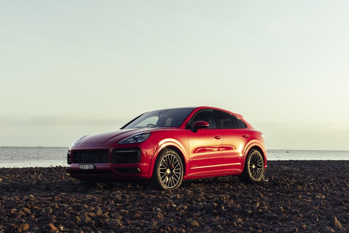 Red Porsche Cayenne GTS Coupé on a rocky beach