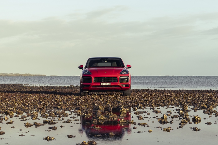 Red Porsche Cayenne GTS Coupé on a reflective beach