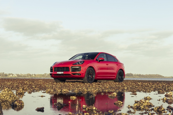 Red Porsche Cayenne GTS Coupé on a rocky shore