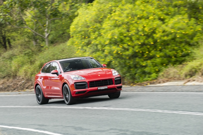 Red Porsche Cayenne GTS Coupé driving on a green road