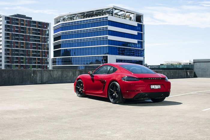 Red Porsche 718 Cayman GTS 4.0 MT with modern buildings