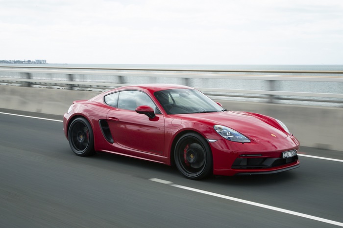 Red Porsche 718 Cayman GTS driving by the sea