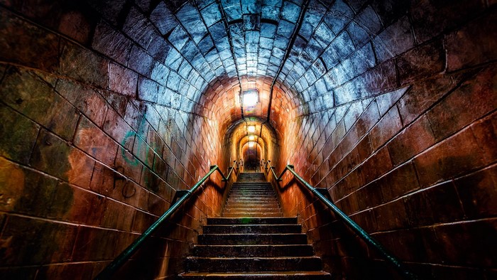 Stairs ascending into a glowing stone tunnel