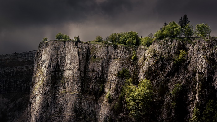 Dramatic Cliff Face with Trees under Dark Sky