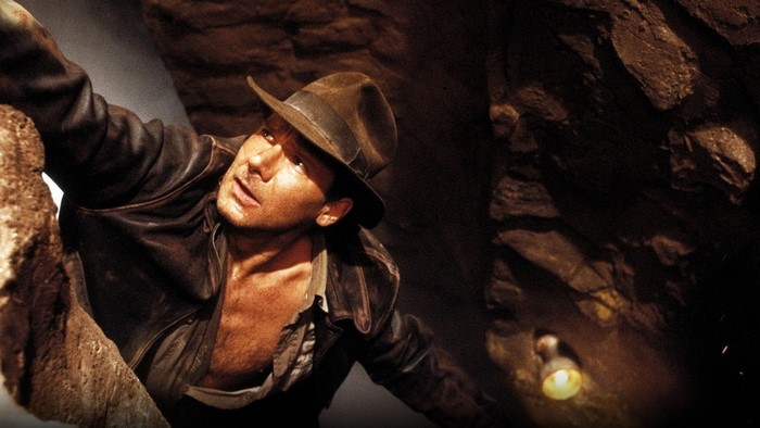 Indiana Jones climbing in a dark cave