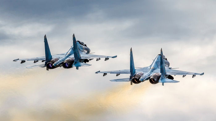 Sukhoi Su-30 warplanes with glowing engines in flight