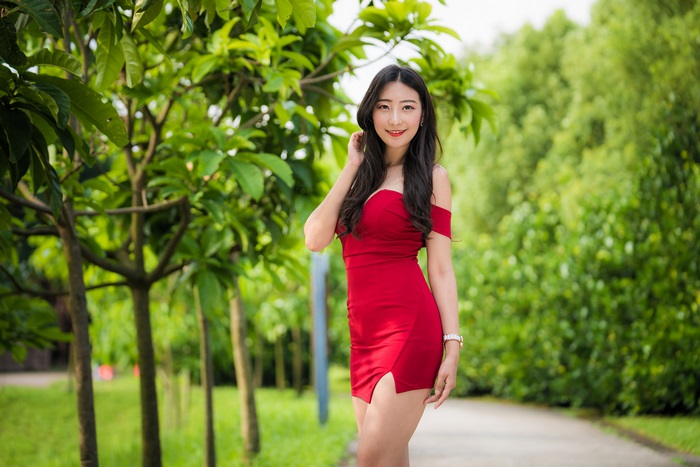 Asian model in red dress smiling outdoors