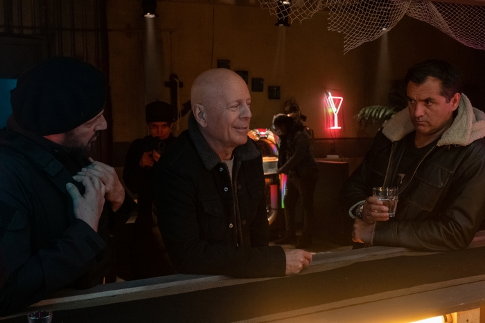 Bruce Willis smiles at a bar in Cosmic Sin.