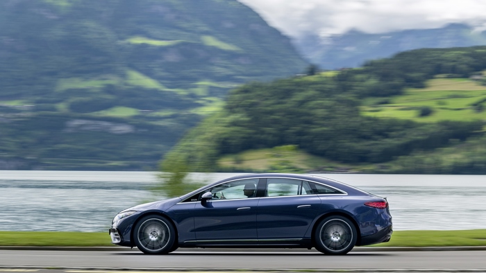 Blue Mercedes-Benz EQS driving by a lake
