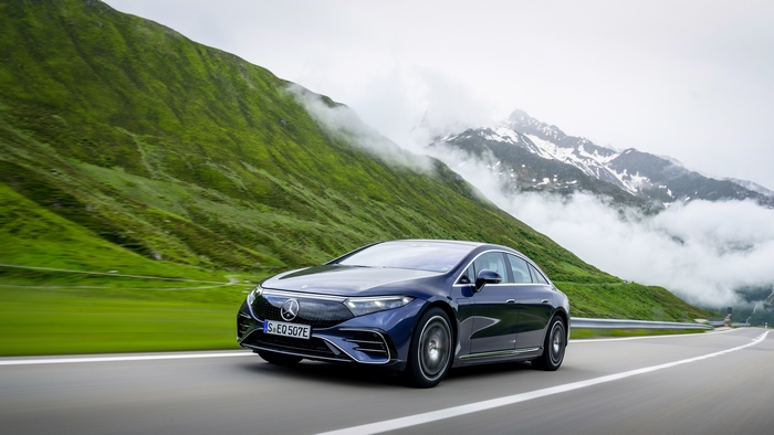 Blue Mercedes-Benz EQS electric car driving in scenic mountains