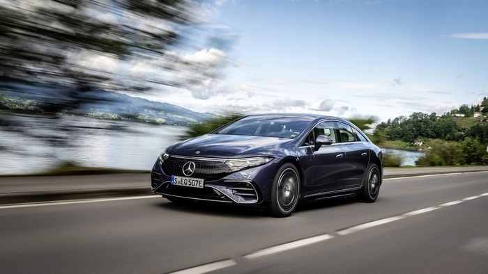 Black Mercedes-Benz EQS electric car driving on scenic road