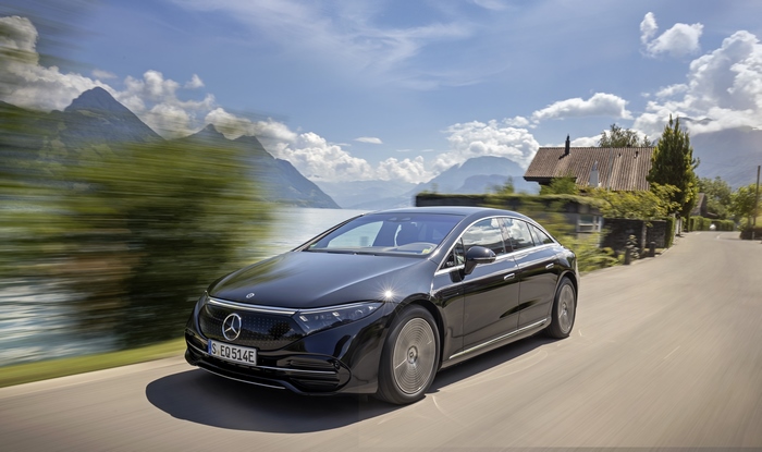 Black Mercedes-Benz EQS driving through a scenic mountain landscape