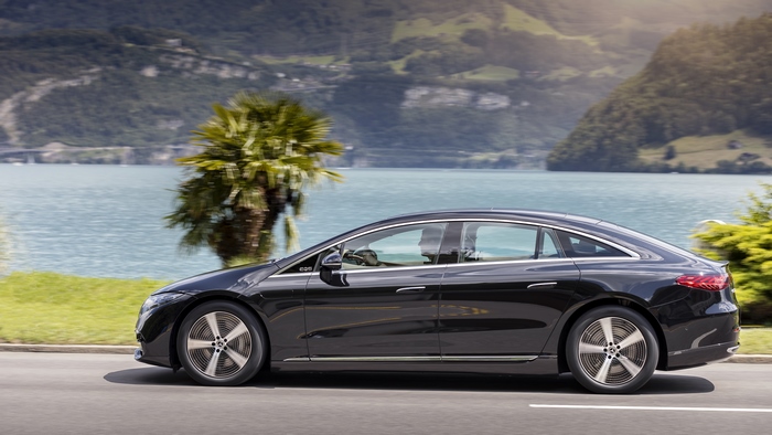 Black Mercedes-Benz EQS electric car driving by a lake