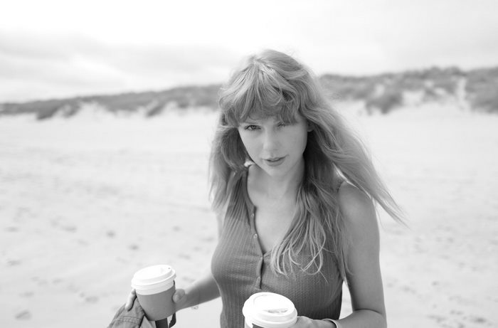 Taylor Swift on the beach holding coffee cups