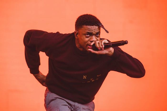 Vince Staples performing with a microphone and fork in hair