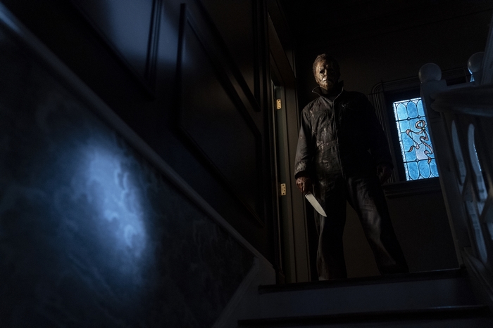 Michael Myers holding a knife on a dark staircase