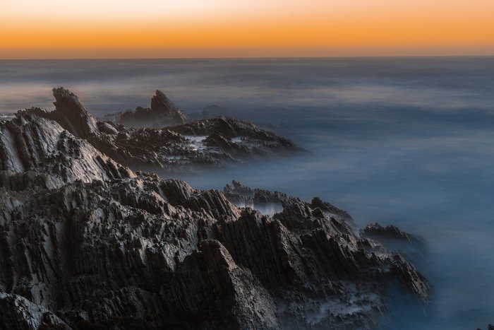 Jagged rocks and misty sea at sunset