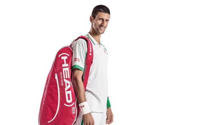 Smiling Novak Djokovic with red HEAD tennis bag