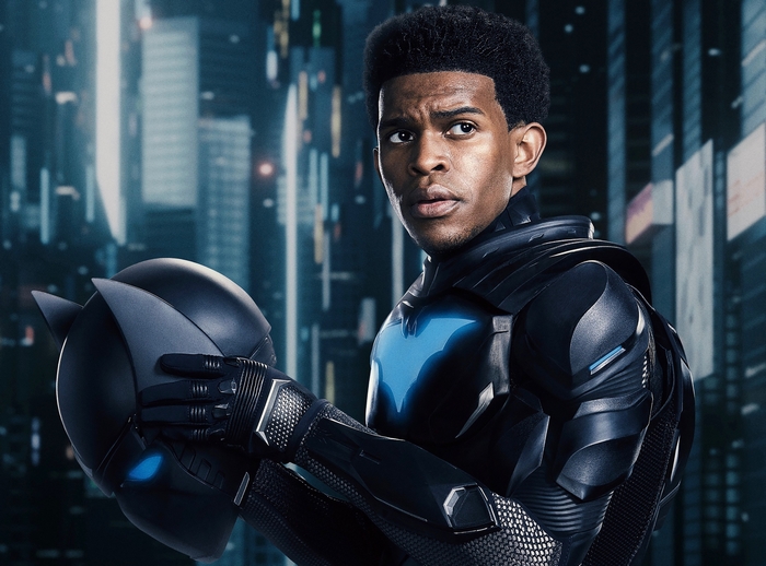 Luke Fox as Batwing holding his helmet