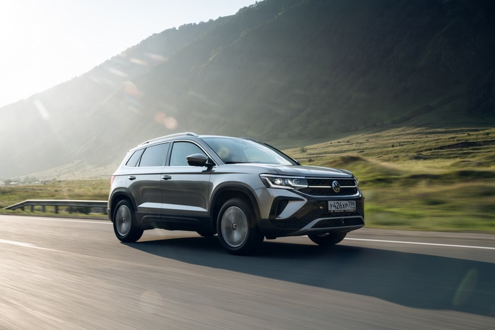 Grey Volkswagen Taos SUV driving through sunny mountains