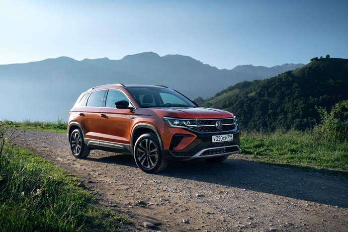 Orange Volkswagen Taos SUV on a scenic mountain road