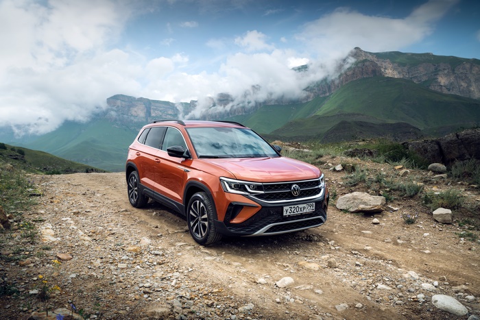Orange Volkswagen Taos SUV in cloudy mountain landscape