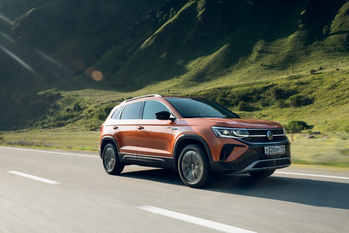 Orange Volkswagen Taos SUV driving on a mountain road