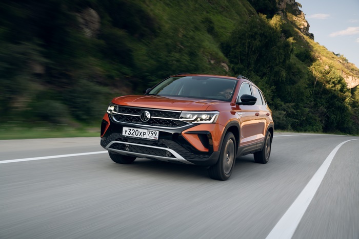 Orange Volkswagen Taos SUV driving on a scenic road