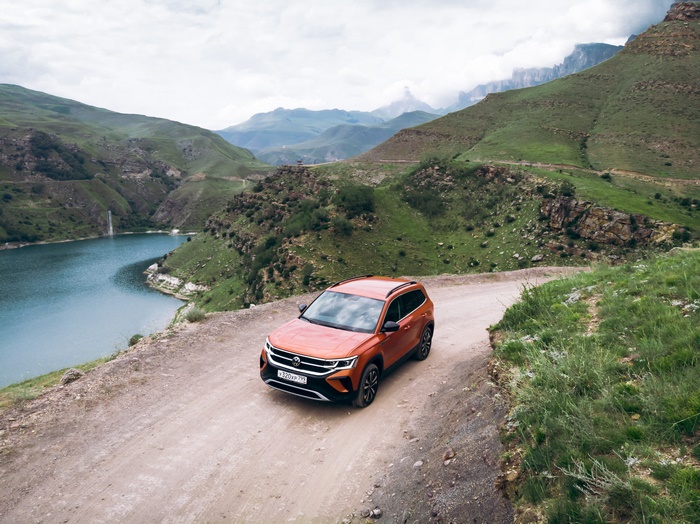 Orange Volkswagen Taos SUV on a scenic mountain road