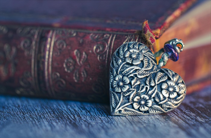 Floral engraved silver heart pendant, macro shot with old book