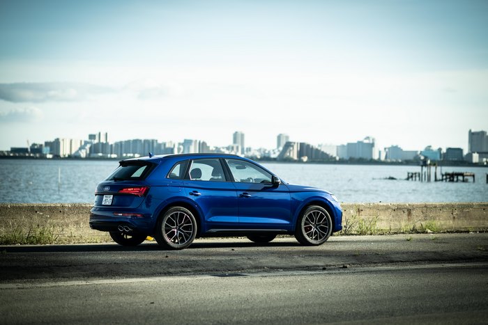 Blue Audi SQ5 SUV by water with city skyline