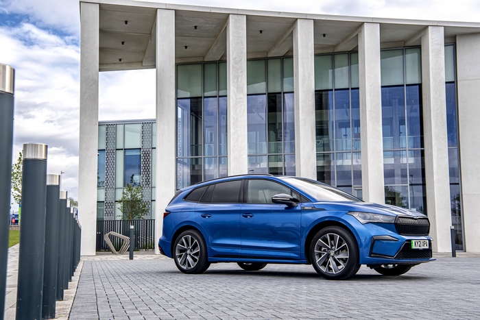 Blue Škoda Enyaq electric SUV in front of modern building