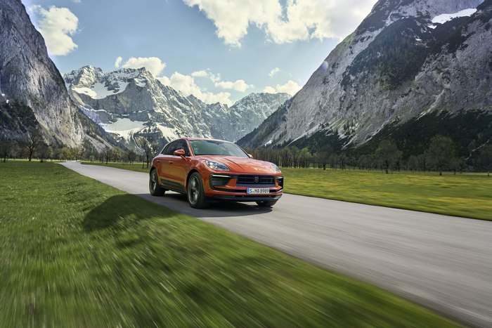 Red Porsche Macan S SUV driving through mountains