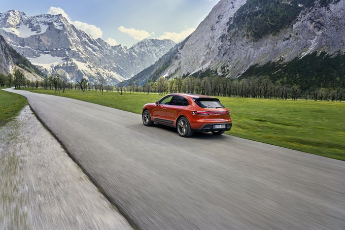 Red Porsche Macan S SUV driving through a mountain valley