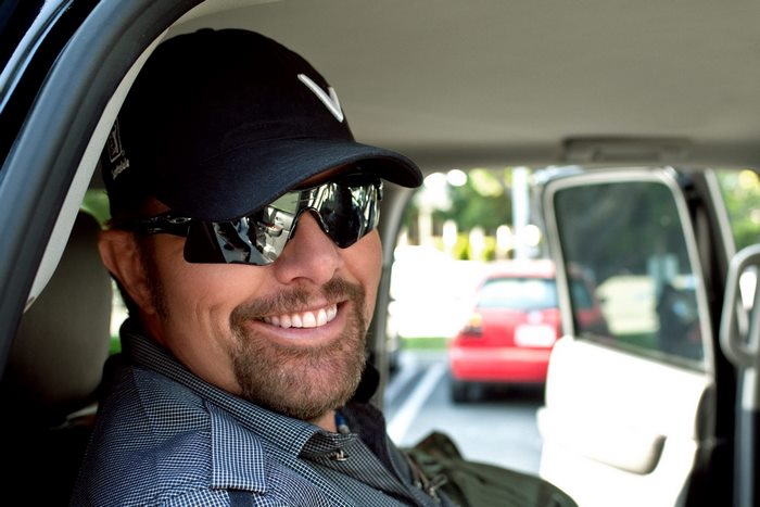 Toby Keith smiling in car with sunglasses
