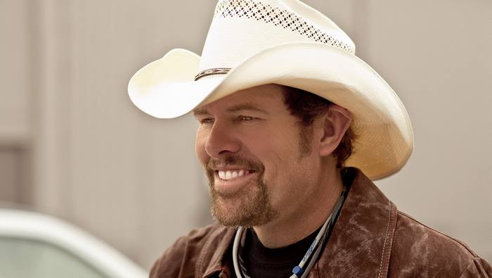 Toby Keith smiling in a white cowboy hat