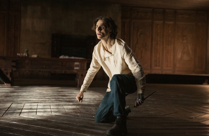 Timothée Chalamet as Paul Atreides kneeling, looking wary in Dune