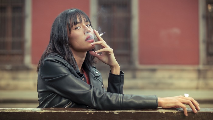 Black-haired model in leather jacket smoking