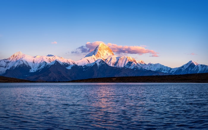 Tibet, China: Golden light on snow mountains and lake