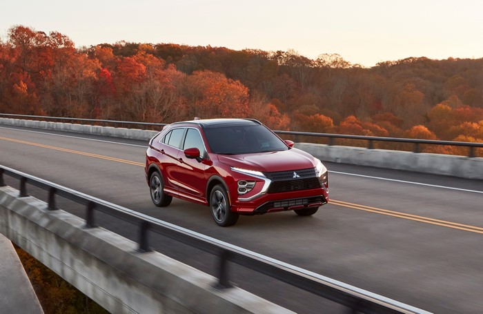 Red Mitsubishi Eclipse Cross SUV on an autumn bridge
