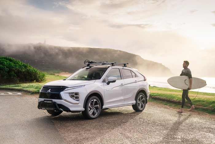 White Mitsubishi Eclipse Cross PHEV with surfer by the coast