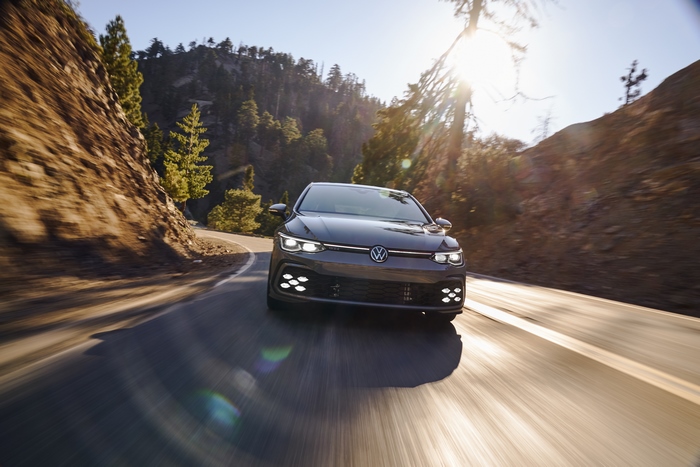 Volkswagen Golf GTI driving on a sunny mountain road