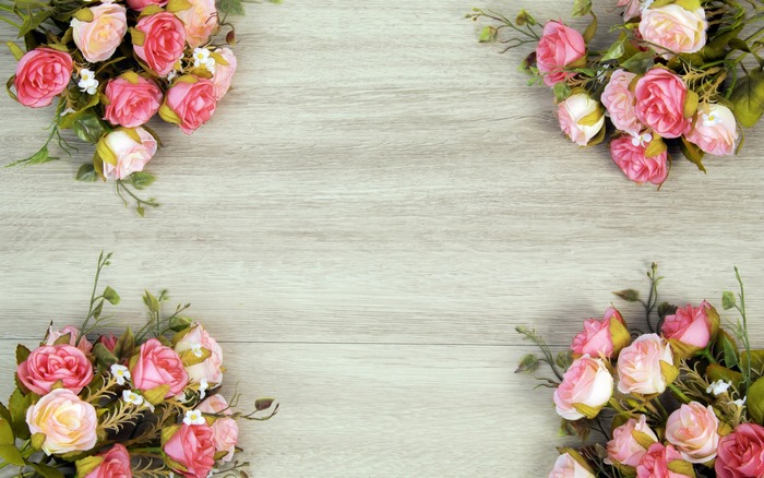 Rose bouquets framing light wooden surface