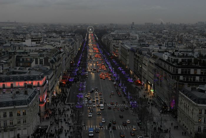 Parisian street at dusk with Christmas lights and traffic