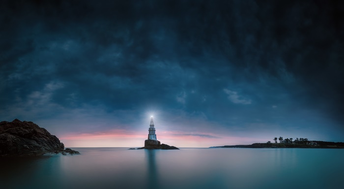 Lighthouse in the dark ocean with dramatic clouds