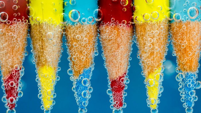 Macro photography of colorful pencils submerged in water with bubbles