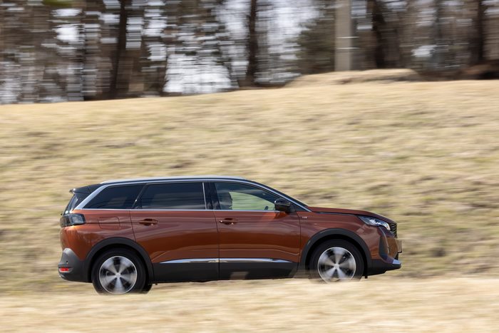 Orange 2021 Peugeot 5008 GT driving on a grassy hill